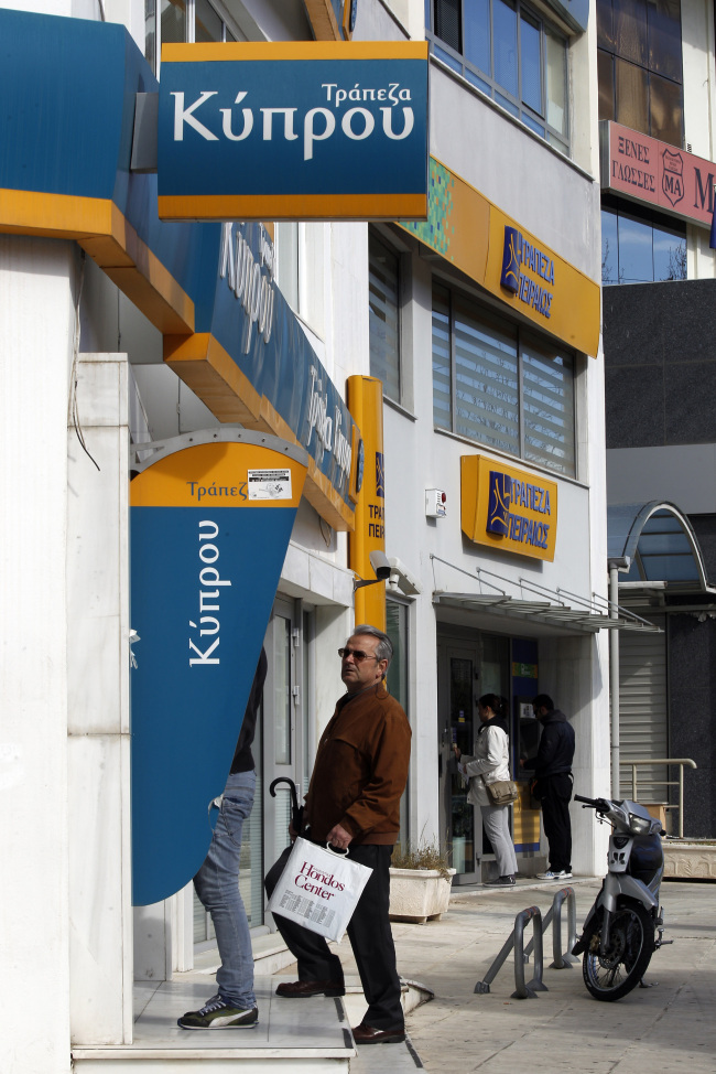 Customers use automated teller machines outside Bank of Cyprus in Athens on Tuesday. (Bloomberg)