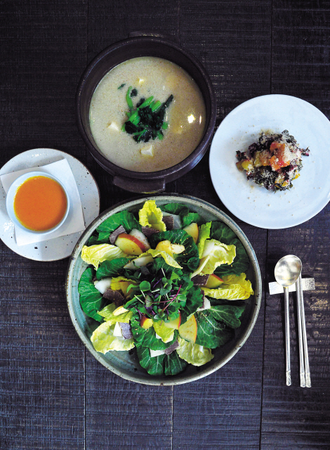 Dadam’s veggie-driven, springappropriate “Sanme” lunch features a crisp spring cabbage salad (center) with a doenjangbased dressing (left), a umamirich perilla seed soup with spring greens (back) and a freeform mugwort rice cake (right). (Lee Sang-sub/The Korea Herald)