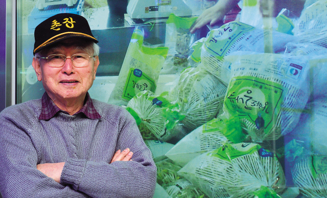 Kim Soung-soo, chief of Urimaul, a community he built for the intellectually challenged to lead a self-reliant life, poses in front of a poster of Urimaul bean sprouts. (Lee Sang-sub/The Korea Herald)