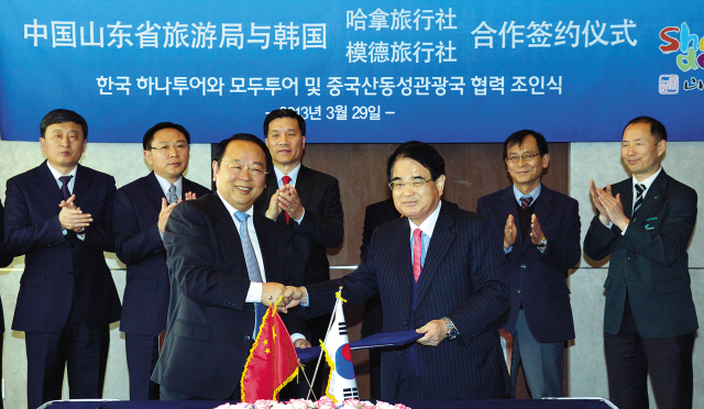 Mode Tour president Hong Ki-jung (right) shakes hands with senior tourism official Yu Chong at China’s Shandong provincial government after signing an agreement to promote joint marketing at a ceremony in Seoul on Friday. (Kim Myung-sub/The Korea Herald)