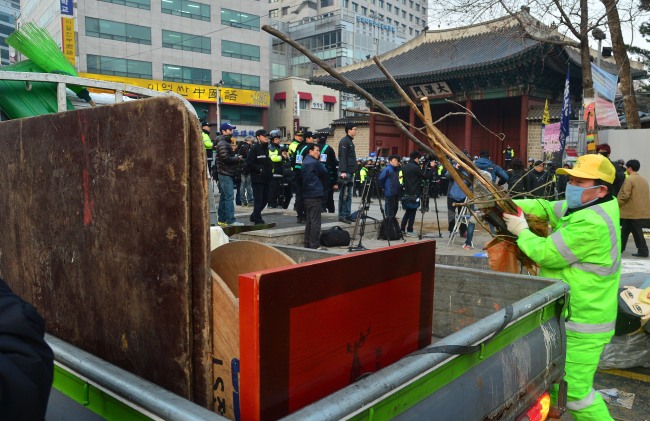 Workers from Jung-gu district office remove tents and desks used by sit-in protesters from Ssangyong Motor Co. since April 2012 in front of Deoksu Palace in central Seoul early Thursday morning. (Lee Sang-sub/The Korea Herald)