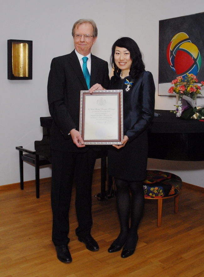 Swedish Ambassador Lars Danielsson (left) and local Korean staffer Bak Hyun-jung hold up a certificate accompanying the Royal Order of the Polar Star she received during a ceremony at the ambassador’s residence in the Seongbuk-dong neighborhood of Seoul, Monday. (Swedish Embassy)