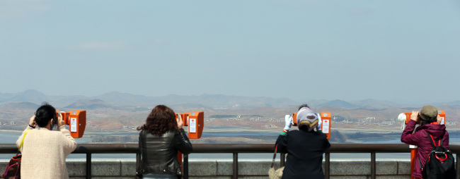 Visitors look through binoculars at North Korea at the Unification Observatory in Paju in northern Gyeonngi Province amid continuing threats of war on Sunday. (Yonhap News)