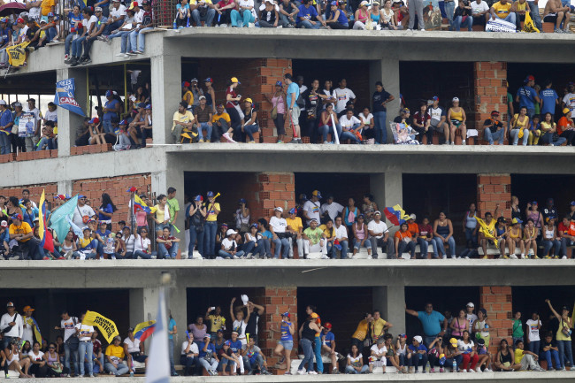 Supporters stand on a building under construction during a campaign rally for opposition presidential candidate Henrique Capriles at Bolivar Avenue in Caracas on Sunday. (AP-Yonhap News)