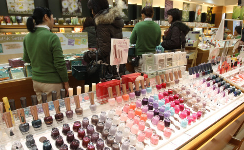 Sales assistants talk with customers at a cosmetic shop. (Yonhap News)