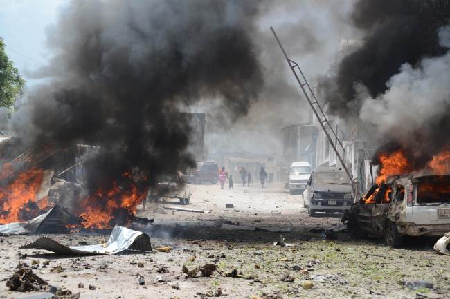 Cars burn in Mogadishu on Sunday, after a suicide bomber attack in the regional court premises that left several dead. (AFP-Yonhap News)