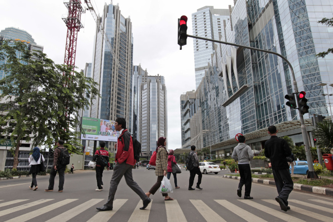 Pedestrians cross a road in front of buildings in the financial district of Jakarta, Indonesia. (Bloomberg)