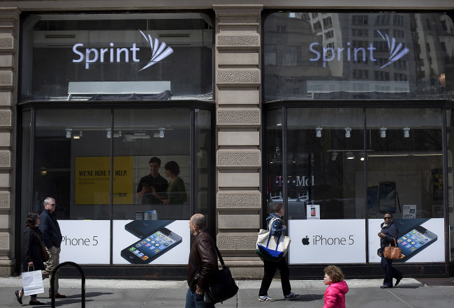 Pedestrians pass in front of a Sprint Nextel Corp. store in New York on Monday. (Bloomberg)