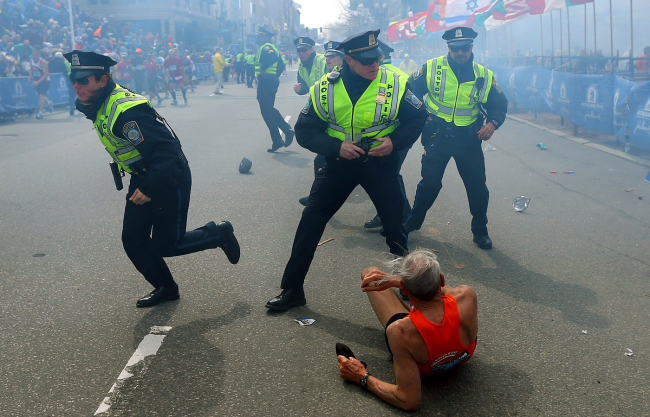 Bill Iffrig, 78, lies on the ground as police officers react to a second explosion at the finish line of the Boston Marathon in Boston, Monday. (AP-Yonhap News)