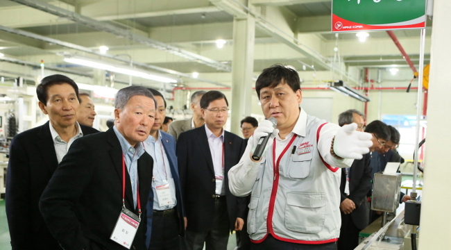 LG Group chairman Koo Bon-moo (left, front) listens to an official from Mirae Korea during his visit to Mirae’s Cheonan factory, which makes TV frames for LG Electronics, on Thursday. (LG Group)