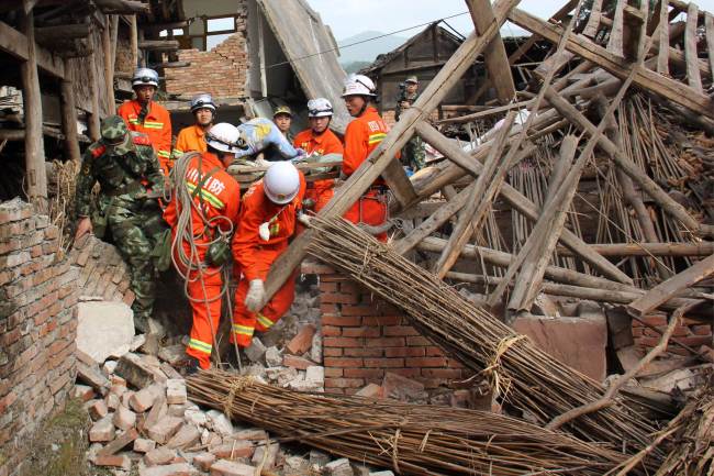 Rescuers carry a paralysed elderly man from his damaged house in Qingren township in seriously damaged Lushan county after a shallow earthquake at magnitude 7.0 hit the city of Ya'an, in southwest China's Sichuan province on April 20, 2013 (AFP-Yonhap)