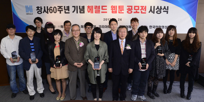 Seung Jeong-yeon (fifth from left), the top prize winner of the Herald Webtoon Contest, poses for a photo with famed cartoonist and chief judge Lee Doo-ho (fourth from left); Lee Young-man (fifth from right), the CEO and publisher of Herald Corp.; Kim Gyeong-yeon, the second-prize winner (fourth from right) and other winners following the award ceremony held at the Herald building in Seoul on Wednesday. (Park Hae-mook/The Korea Herald)