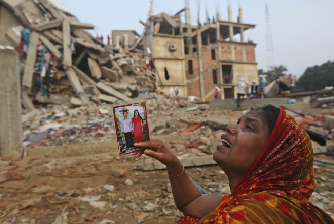 A Bangladeshi woman weeps as she holds a picture of her and her missing husband as she waits at the site of a building that collapsed Wednesday in Savar, near Dhaka, Bangladesh, Friday. (AP-Yonhap News)