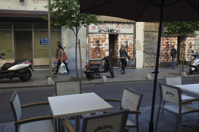 Pedestrians pass closed-down stores opposite an empty cafe terrace in Madrid. (Bloomberg)