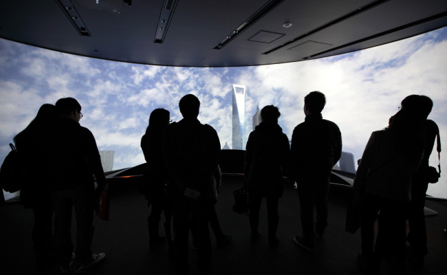 Visitors look at a monitor displaying an image of the Shanghai World Financial Center in the Pudong area of Shanghai. (Bloomberg)