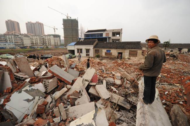 A worker looks out over the rubble where Yao Baohua’s house (center from behind) still stands in the city of Changzhou in China’s eastern Jiangsu province. (AFP-Yonhap News)