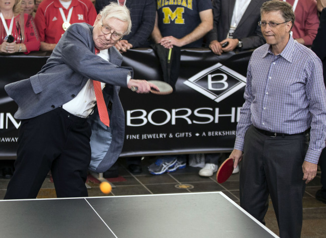 Berkshire Hathaway Chairman and CEO Warren Buffett (left) smashes the ball, as he and Microsoft founder and Berkshire director Bill Gates play table tennis against U.S. national champion Ariel Hsing (unseen), outside Borsheims jewelry store, a Berkshire Hathaway subsidiary, in Omaha, Nebraska, Sunday. (AP-Yonhap News)