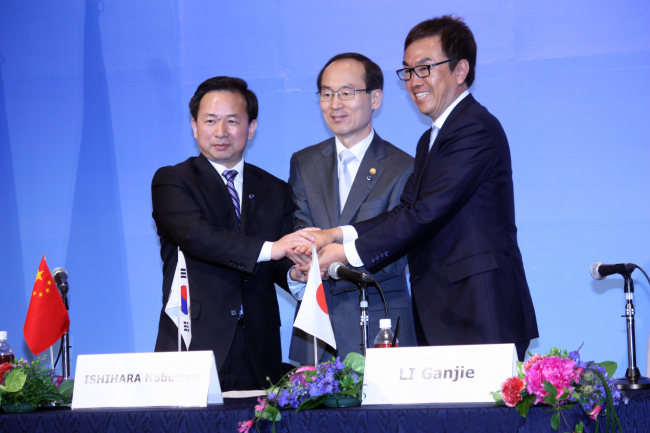 Environment Minister Yoon Seong-kyu (center), his Japanese counterpart Nobuteru Ishihara (right) and Chinese Environmental Protection Vice Minister Li Ganjie join hands after signing a joint communique in Kitakyushu, Japan on Monday. (Yonhap News)