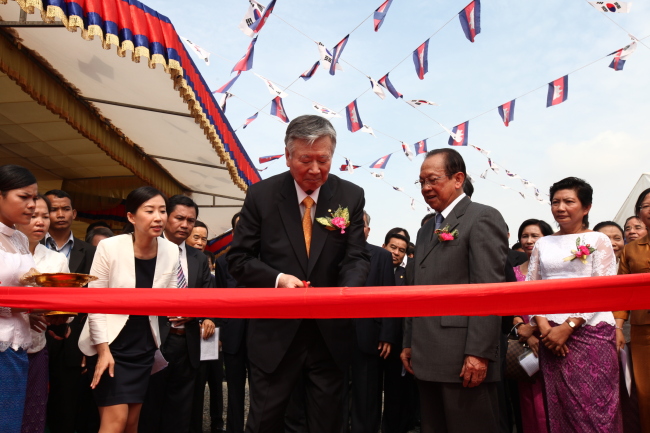 Booyoung Group chairman Lee Joong-keun cuts the ribbon at the groundbreaking ceremony for Booyoung Town in Phnom Penh, Cambodia, Tuesday. Cambodian Land Minister Im Chhun Lim looks on. (Booyoung Group)