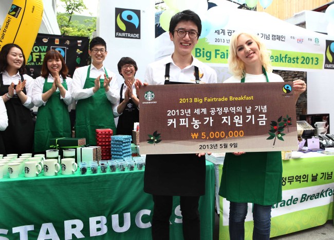 Starbucks coffee ambassador in Korea Choi Yong-seok (left) on Thursday signed up to donate 5 million won for smaller coffee producers to Bronwyn Mullen, a goodwill ambassador to Korea from the World Fair Trade Organization, in Sinsa-dong, southern Seoul, as a part of the company’s fair trade campaign for World Fair Trade Day, which is Saturday. (Starbucks)