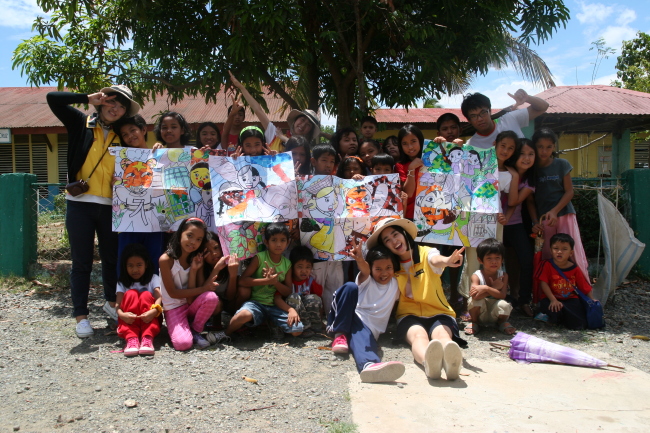 “RaonAtti,” a team of college volunteers organized by KB Kookmin Bank and YMCA Korea, pose with local children in the Philippines. (KB Financial Group)