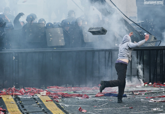 A PSG supporter throws a concrete block toward riot police in Paris on Monday. (AP-Yonhap News)