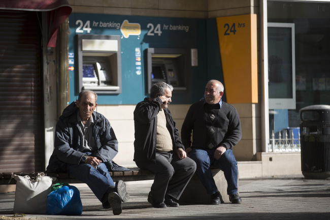 Men sit near 24-hour automated teller machines operated by Bank of Cyprus in Nicosia, Cyprus. (Bloomberg)