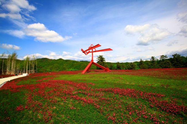 Mark di Suvero’s red steel sculpture “For Gerard Manley Hopkins” stands in the flower garden. (Hansol Museum)