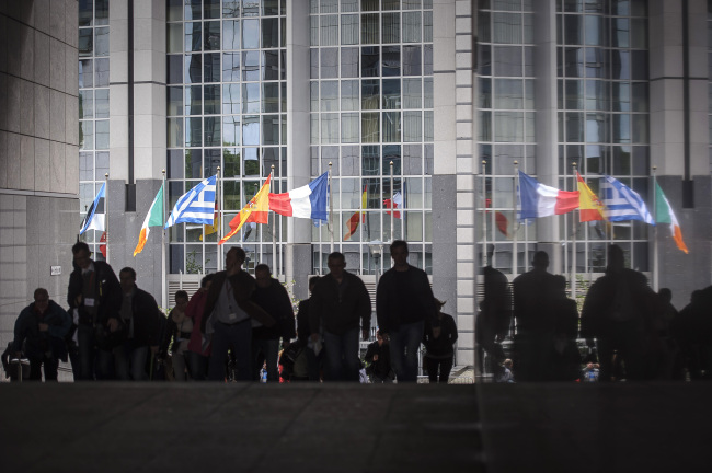 Pedestrians walk past the European Union parliament building and the national flags of the member states in Brussels. (Bloomberg)