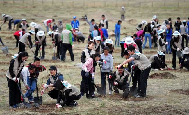 Korean Air employees and Mongolian children plant trees in the Baganor Desert near Ulan Bator, Mongolia, on Wednesday. Korean Air has cultivated the Korean Air Forest in the desert since 2004 when it launched the Global Planting Project. (Yonhap News)