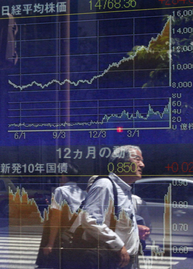 Pedestrian are reflected in an electronic stock board in Tokyo on Friday. (Bloomberg)