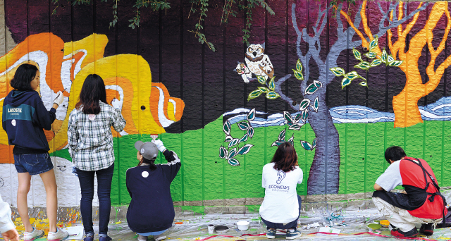 Students paint murals of Korean folktales on the walls of Sageun Elementary School in Seoul. (Yonhap News)