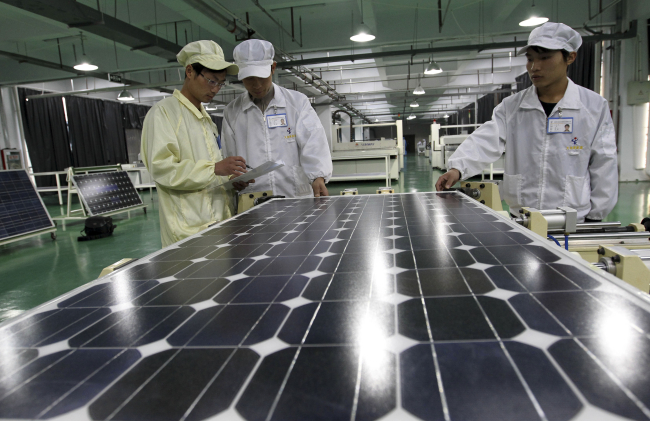 Chinese workers examine solar panels at a manufacturer of photovoltaic products in Huaibei, Anhui province in March 2012. (AP-Yonhap News)