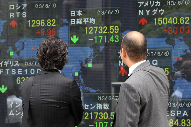 Pedestrians look at an electronic stock board in Tokyo on Friday. ( Bloomberg)