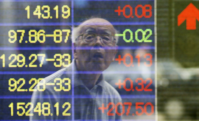 A man is reflected on the electronic board of a securities firm in Tokyo on Monday. (AP-Yonhap News)