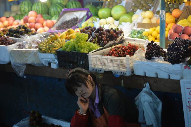 A fruit vendor takes a nap at a market in Shanghai on Sunday. ( AFP-Yonhap News)