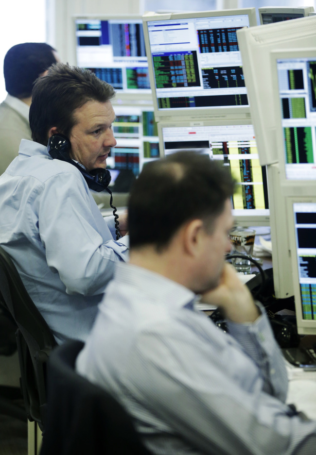 A stockbroker talks on the phone as he monitors financial data on computer screens at Shore Capital Group Ltd. brokerage in London. (Bloomberg)