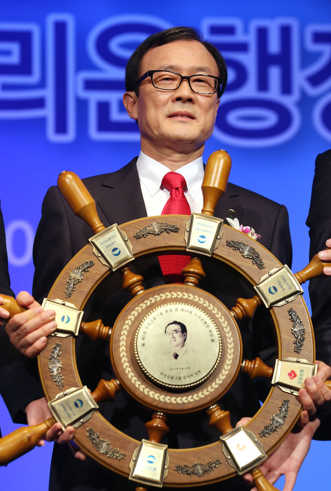 New Woori Financial Group chairman Lee Soon-woo poses with a memorial tablet presented by the group’s staff at his inaugural ceremony in Seoul on Friday. (Yonhap News)