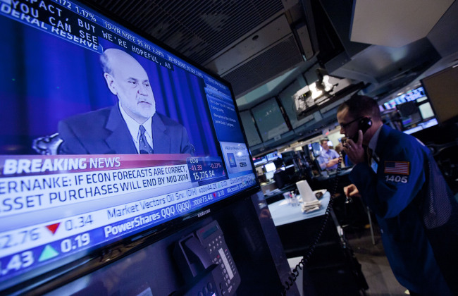 Traders work on the floor of the New York Stock Exchange as Ben Bernanke, chairman of the U.S. Federal Reserve, speaks on television in New York on Wednesday. (Bloomberg)