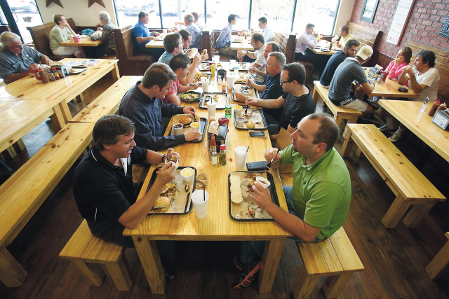 Robert Stanley (foreground left) and Tim Behling (right), sit at communal table on June 5 to have lunch at 4Rivers Smokehouse in Winter Park, Florida. (MCT)