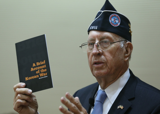 Larry Kinard, president of the Korean War Veterans Association, holds “A Brief Account of the Korean War” published to educate U.S. students about the war during his lecture at the Korea Military Academy in Seoul on Friday. (Yonhap News)