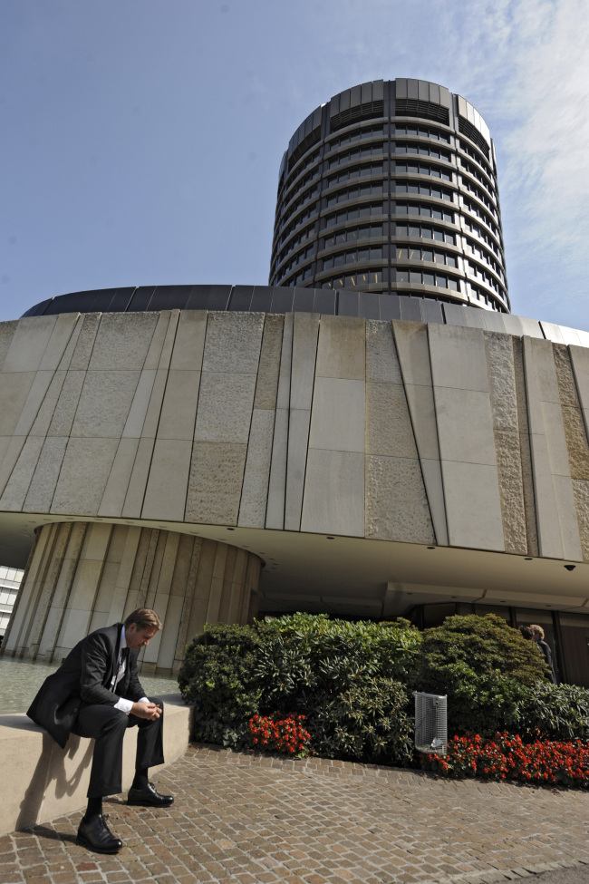 A businessman sits in front of the Bank for International Settlements in Basel, Switzerland. (Bloomberg)