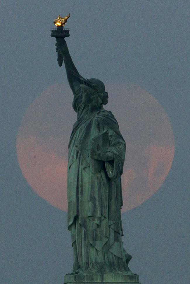 A supermoon sets behind the Statue of Liberty in New York on Sunday. (AP-Yonhap News)