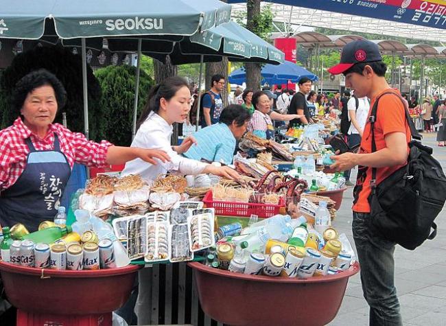 A man buys snacks from a vendor in front of Jamsil Stadium. (Bae Ji-sook/The Korea Herald)