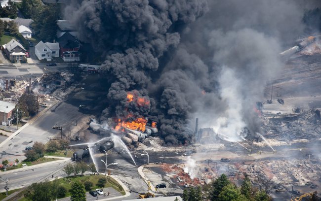 Smoke rises from railway cars that were carrying crude oil after derailing in downtown Lac Megantic, Quebec, Canada, Saturday, July 6, 2013. A large swath of Lac Megantic was destroyed Saturday after a train carrying crude oil derailed, sparking several explosions and forcing the evacuation of up to 1,000 people. (AP/Yonhap)