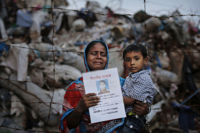 A woman holds a picture of her son, a garment worker who went missing following the collapse of the Rana Plaza building in Savar, Dhaka, Bangladesh, June 14. (AP-Yonhap News)