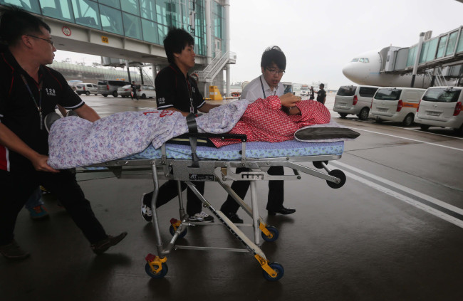 Airport staff transfer a Korean passenger who survived Asiana Airlines flight 214, which crash-landed at San Francisco Airport this weekend, to a hospital upon arrival at Incheon International Airport on Monday. (Kim Myung-sub/The Korea Herald)