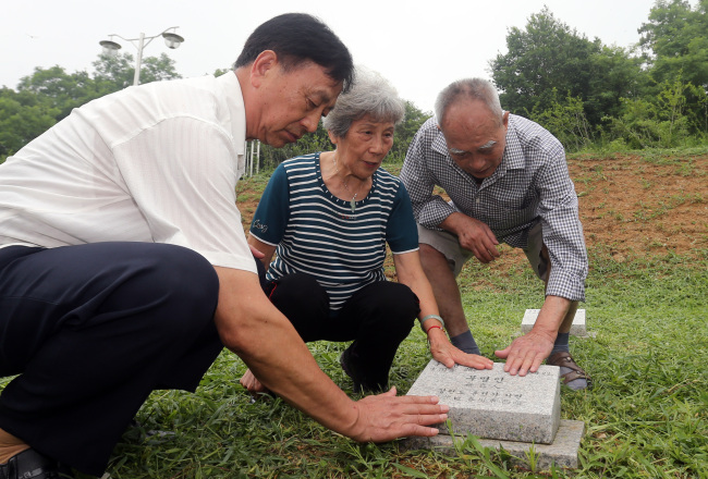 Three Chinese veterans of the Korean War, Liang Deng Gao (left), Chen Ruo Bi (center) and Lai Xuex Ian, touch a gravestone at a cemetery for Chinese and North Koreans who died in the Korean War in Paju, Gyeonggi Province, Tuesday. (Yonhap News)