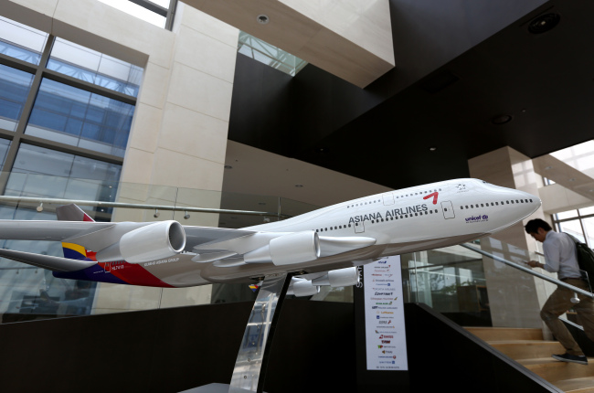 A man using a mobile phone walks past an Asiana Airlines Inc. model aircraft displayed at the company’s headquarters in Seoul. (Bloomberg)