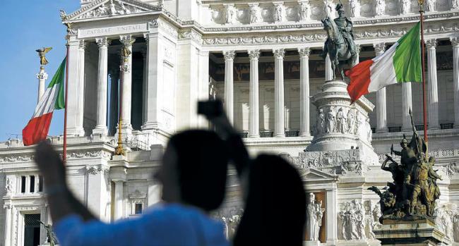 Tourists take photographs in front of a monument to the unknown soldier in Rome. (Bloomberg)